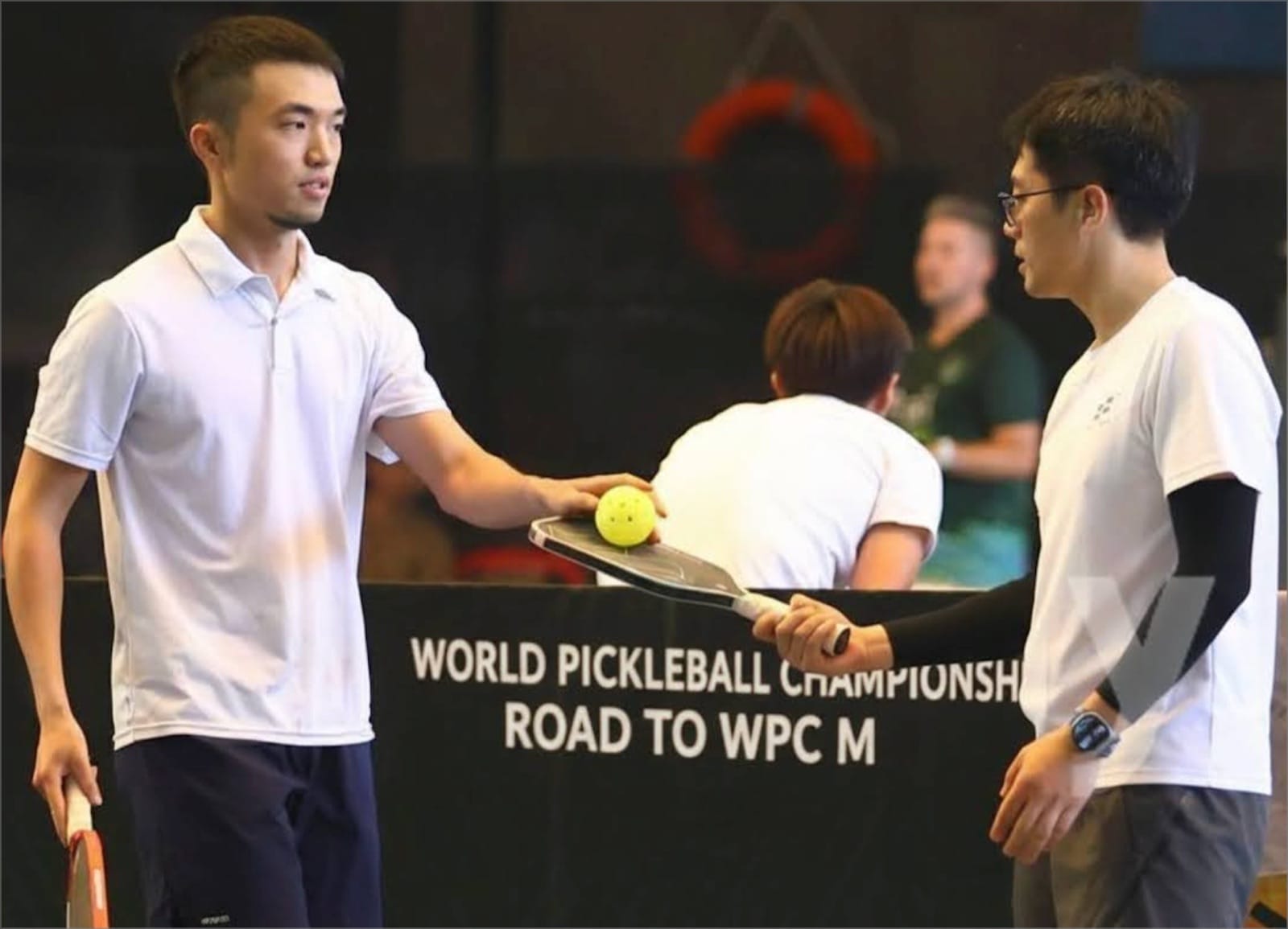 Shiuan（梁文宣）與搭檔 Kevin 在 2025 年峇里島 WPC 匹克球賽場上拿著球拍討論